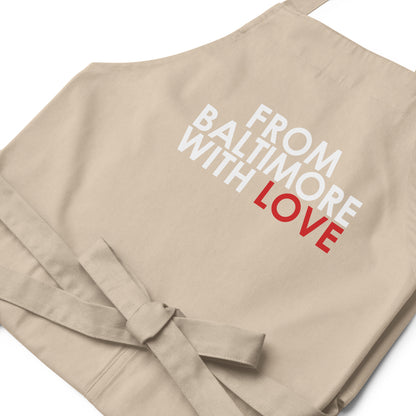 Red cotton apron by From Baltimore With Love™ featuring classic design, shown hanging with adjustable neck strap.