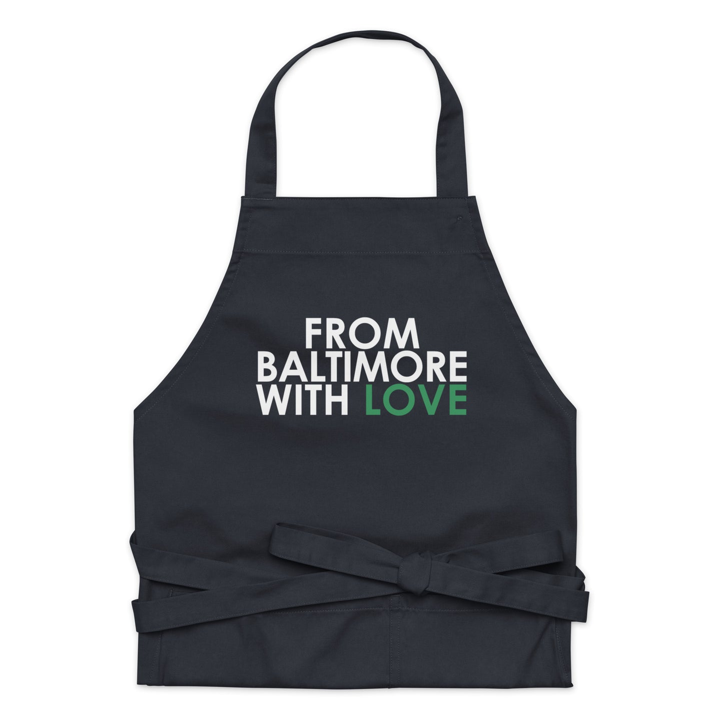 Green cotton apron by From Baltimore With Love™ with adjustable straps, shown hanging on a hook.