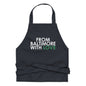 Green cotton apron by From Baltimore With Love™ with adjustable straps, shown hanging on a hook.