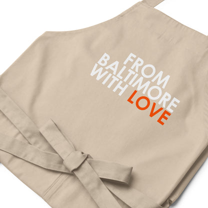 Orange cotton apron by From Baltimore With Love™ with black straps and pockets, designed for cooking or crafting.