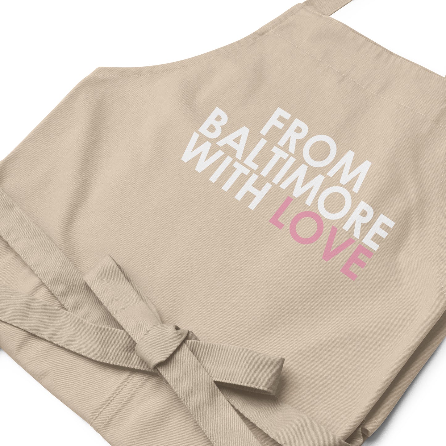 Pink cotton apron from Baltimore With Love™ featuring the FBWL logo, ideal for cooking or crafting activities.