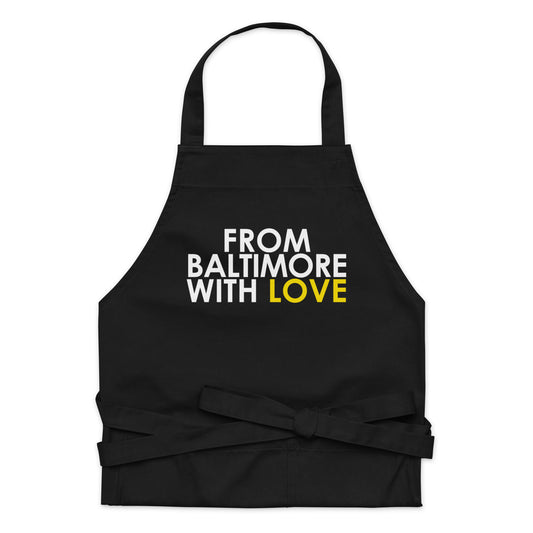 Yellow cotton apron by From Baltimore With Love™ with black straps and pockets, perfect for cooking or gardening.
