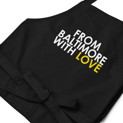 Yellow cotton apron from From Baltimore With Love™ featuring black straps and logo for cooking or baking use.