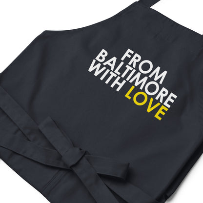Yellow cotton apron by From Baltimore With Love™ featuring black branding, shown hanging with adjustable neck strap.